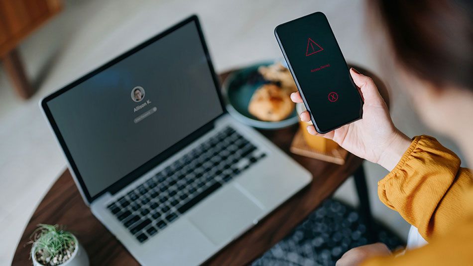 hand holding phone and laptop