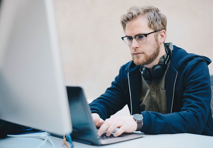Man with glasses working on a laptop